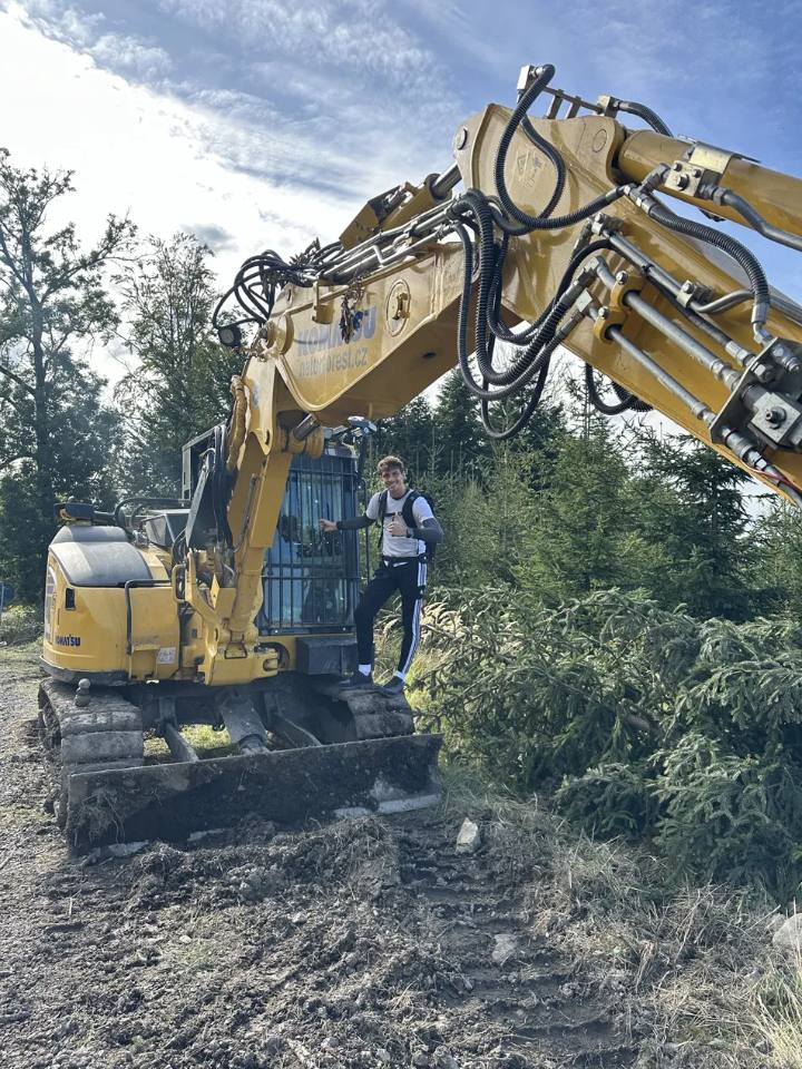 Projektant přípojek stojí na rypadle na stavbě